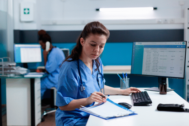 Profissionais da saúde utilizando computador e documentos, representando a importância do outsourcing de impressão para hospitais.